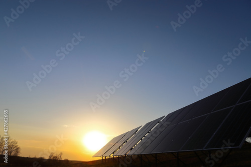 Photovoltaic batteries at orange sunset. Solar panels. Alternative energy concept