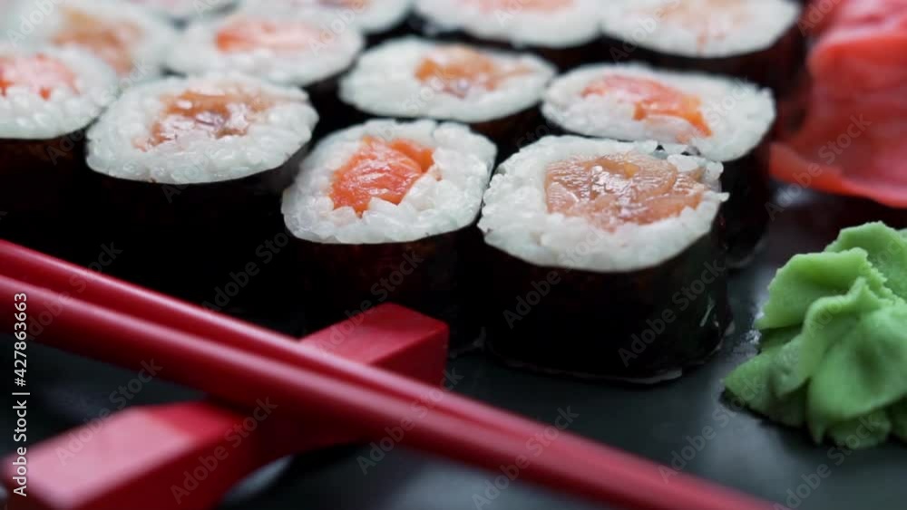 Sushi with Spices on a Black Dish with Red Sticks, Rotation, Macro. Japanese Cuisine Dish. Sushi with Spices on a Black Dish with Red Sticks, Rotation, Macro. Japanese Cuisine Dish.