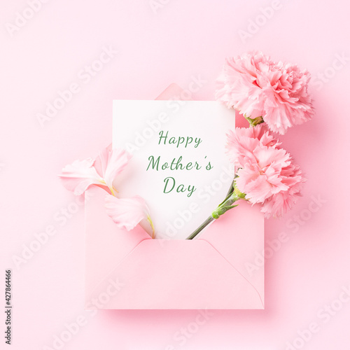 Happy Mother's Day card in pink envelope with carnations on pink background. © Olga Zarytska