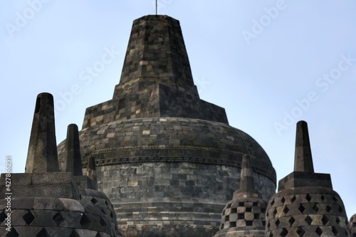 Interior of ancient Borobudur Temple. View of stupas on upper terrace with clear blue sky. No people. Popular tourist and Buddhist pilgrimage destination. For wallpaper or background. 