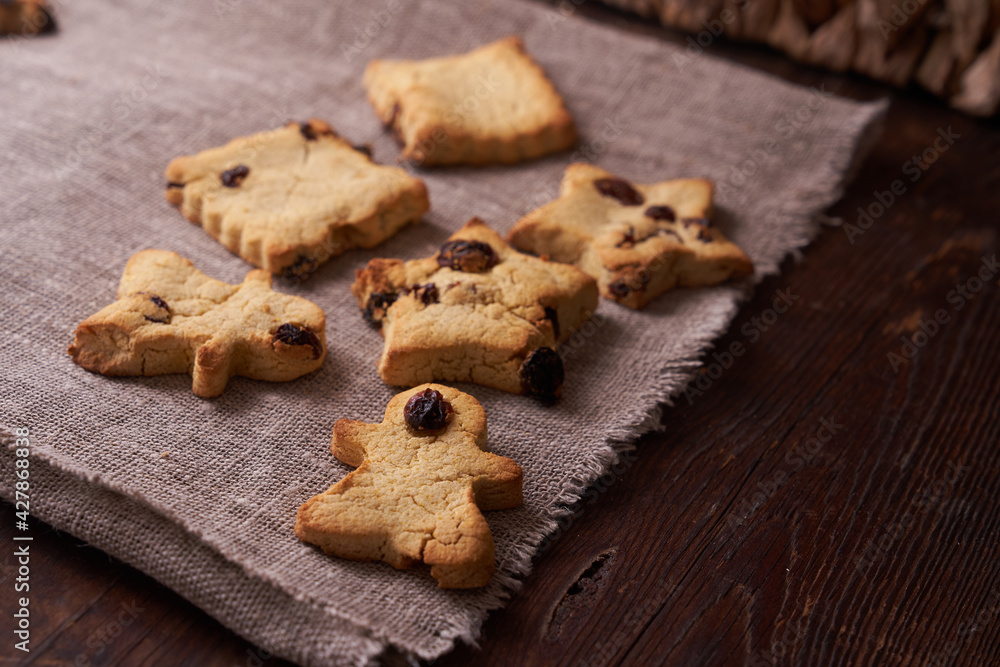 Healthy homemade gluten-free, lactose-free cookies of various shapes without sugar with raisins and chocolate on a dark brown wooden background