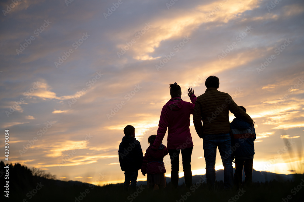 Silhouette of a family standing under beautiful evening sky looking into the distance