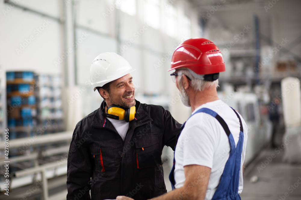Portrait of workers in factory. Colleagues with helmet working in factory Portrait of workers in factory. Colleagues with helmet working in factory