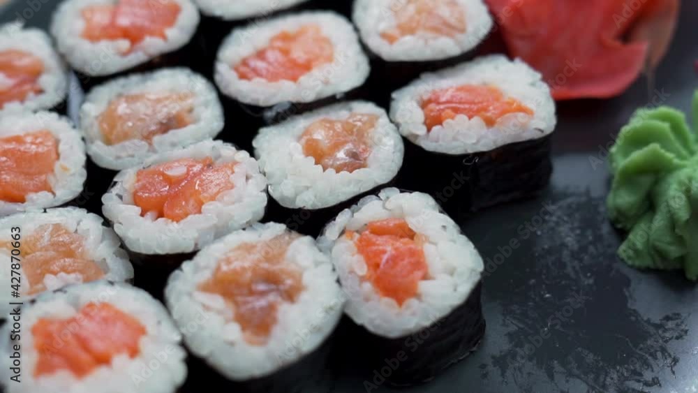 Eating a Delicious Lunch of Fresh Sushi Rolls with a Black Platter, Close-up. Hand Takes Sushi, Macro, CloseUp. Japanese Dish, Japanese Delicacy, Healthy Asian Seafood Meal. Eating a Delicious Lunch of Fresh Sushi Rolls with a Black Platter, Close-up. Hand Takes Sushi, Macro, CloseUp. Japanese Dish, Japanese Delicacy, Healthy Asian Seafood Meal.