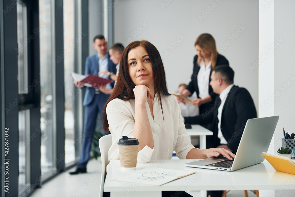 Woman in front of her colleagues. Group of people in official formal clothes that is indoors in the office Woman in front of her colleagues. Group of people in official formal clothes that is indoors in the office