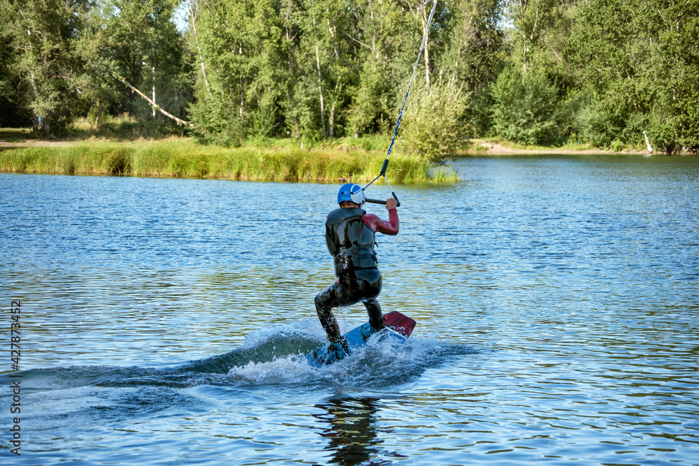 A man wakeboarding on a lake on summer day in a life jacket. Soft focus. Action blur. A man wakeboarding on a lake on summer day in a life jacket. Soft focus. Action blur.