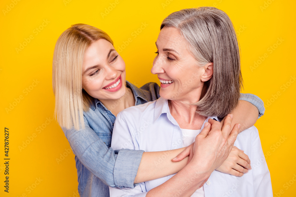 Photo portrait of mother and daughter cuddling together smiling isolated bright yellow color background Photo portrait of mother and daughter cuddling together smiling isolated bright yellow color background
