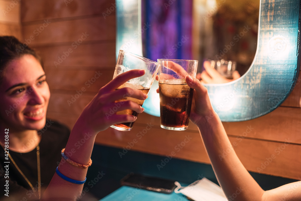 Dos chicas en un bar brindando con refresco