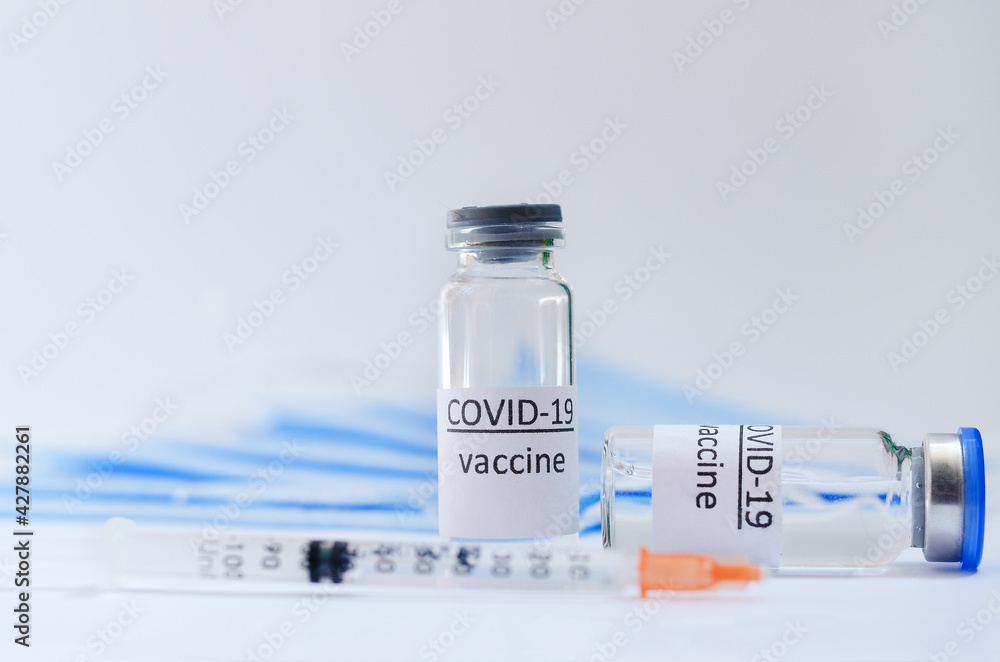 Creative ideas of vaccination concept. Top view of syringe with medical masks and vaccine vial glass bottles for vaccination against COVID-19. Coronavirus pandemic. Copy space. Creative ideas of vaccination concept. Top view of syringe with medical masks and vaccine vial glass bottles for vaccination against COVID-19. Coronavirus pandemic. Copy space.
