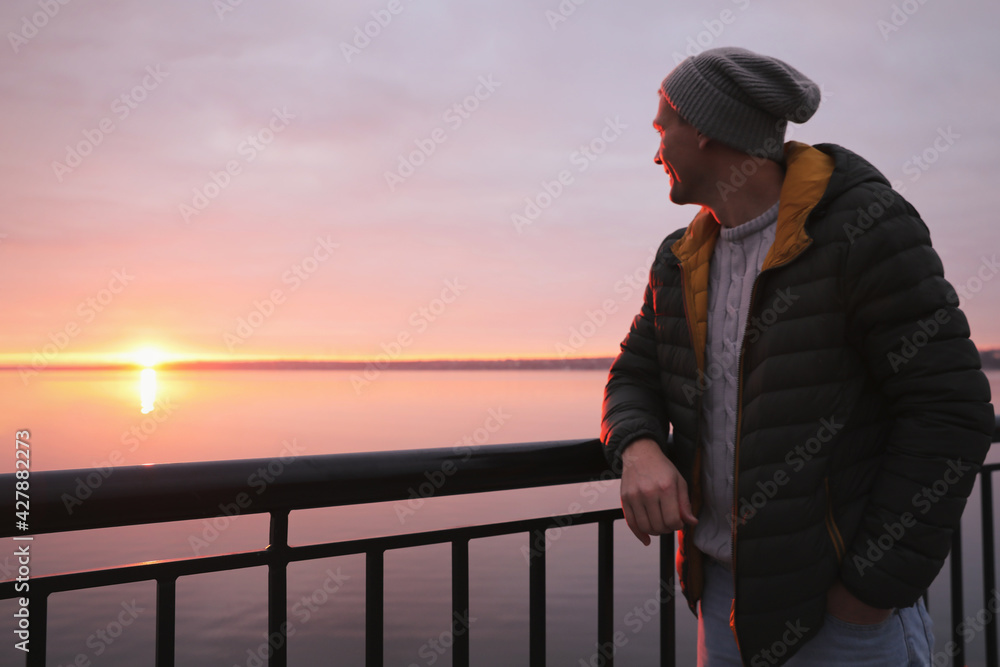 Man standing near river at sunset, space for text Man standing near river at sunset, space for text