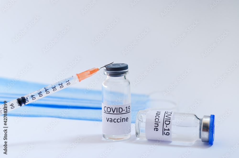 Creative ideas of vaccination concept. Top view of syringe with medical masks and vaccine vial glass bottles for vaccination against COVID-19. Coronavirus pandemic. Copy space. Creative ideas of vaccination concept. Top view of syringe with medical masks and vaccine vial glass bottles for vaccination against COVID-19. Coronavirus pandemic. Copy space.