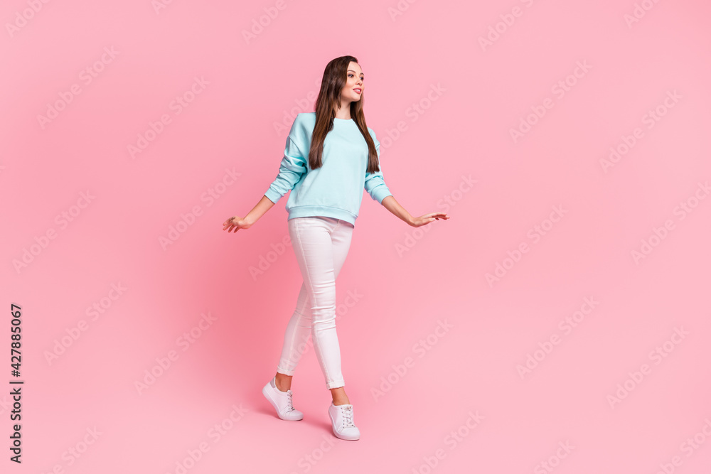 Full size portrait of young walking person look empty space wear light blue pullover isolated on pink color background