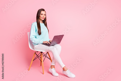 Full body profile portrait of positive person distance work laptop on knees wear sweater isolated on pink color background