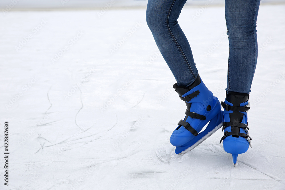 Woman wearing figure skates on ice rink, closeup. Space for text