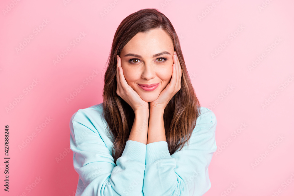Photo of calm attractive young woman hold hands cheeks charming smile isolated on pink color background Photo of calm attractive young woman hold hands cheeks charming smile isolated on pink color background