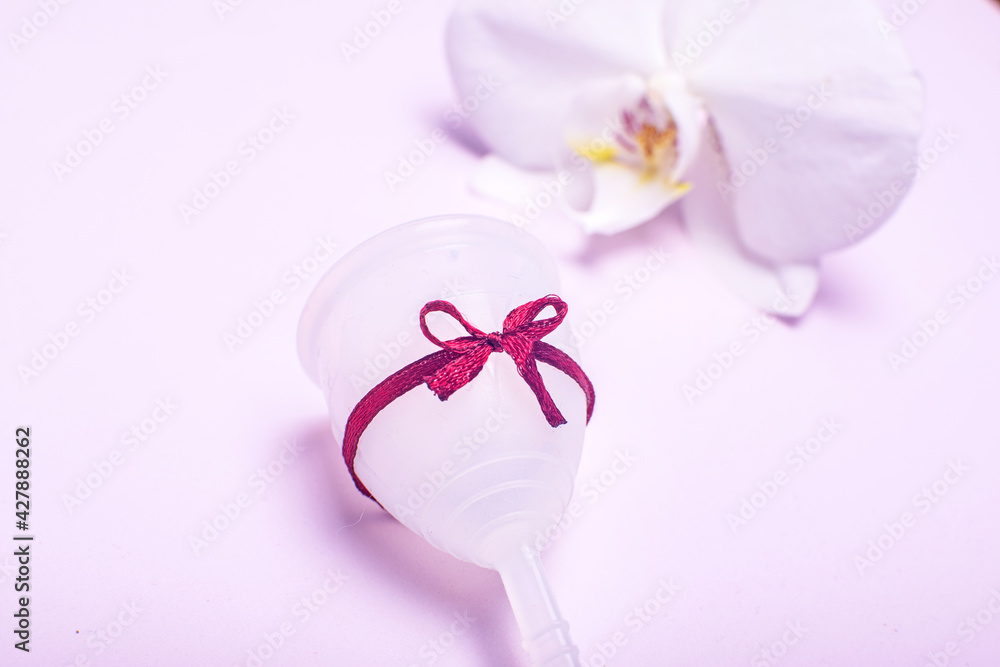 Eco-friendly silicone menstrual cup with orchid on pink background. Eco-friendly silicone menstrual cup with orchid on pink background.