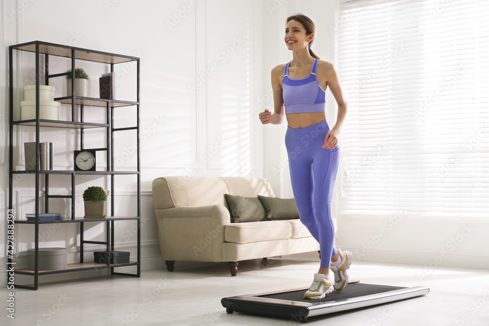 Sporty woman training on walking treadmill at home Sporty woman training on walking treadmill at home