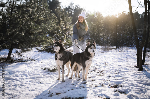 Young woman with dogs in forest on winter day