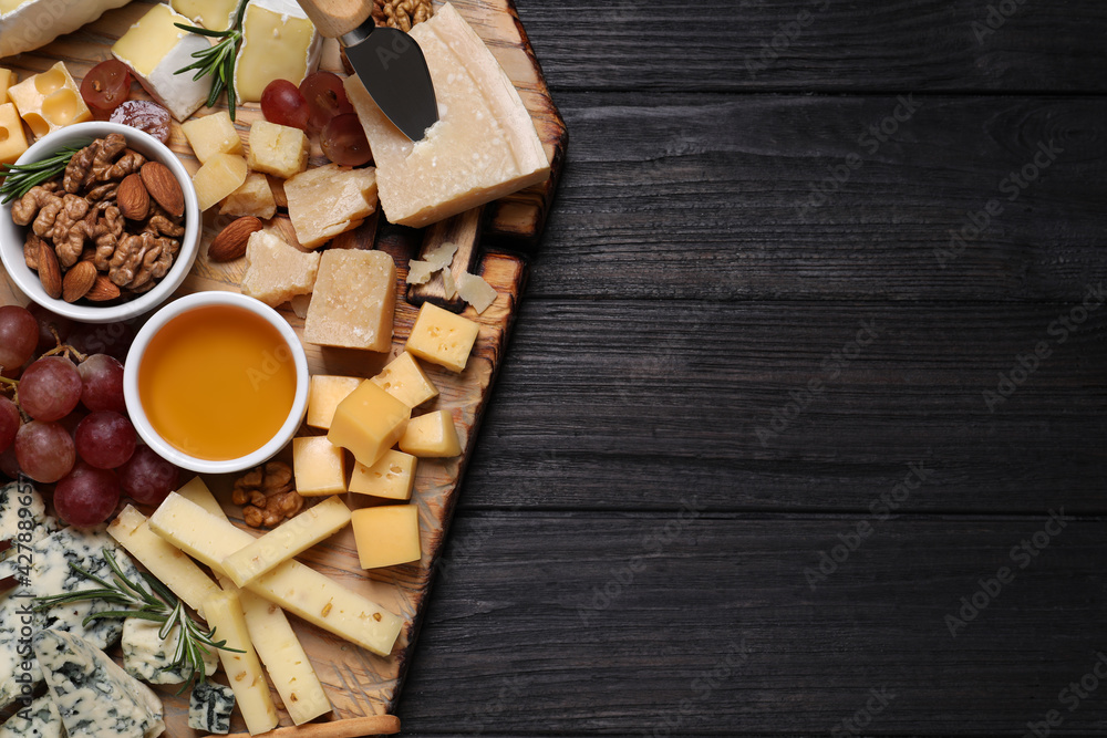 Cheese plate with honey, grapes and nuts on black wooden table, top view. Space for text Cheese plate with honey, grapes and nuts on black wooden table, top view. Space for text