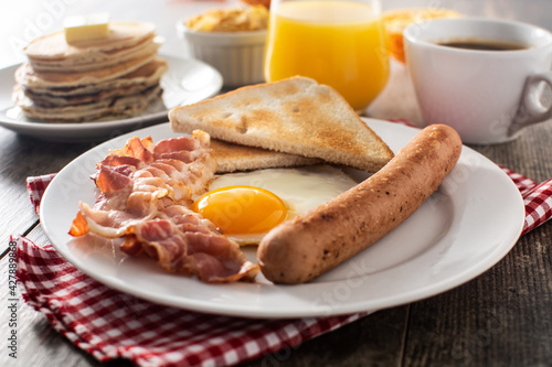 Traditional American breakfast with fried egg,toast,bacon and sausage on wooden table