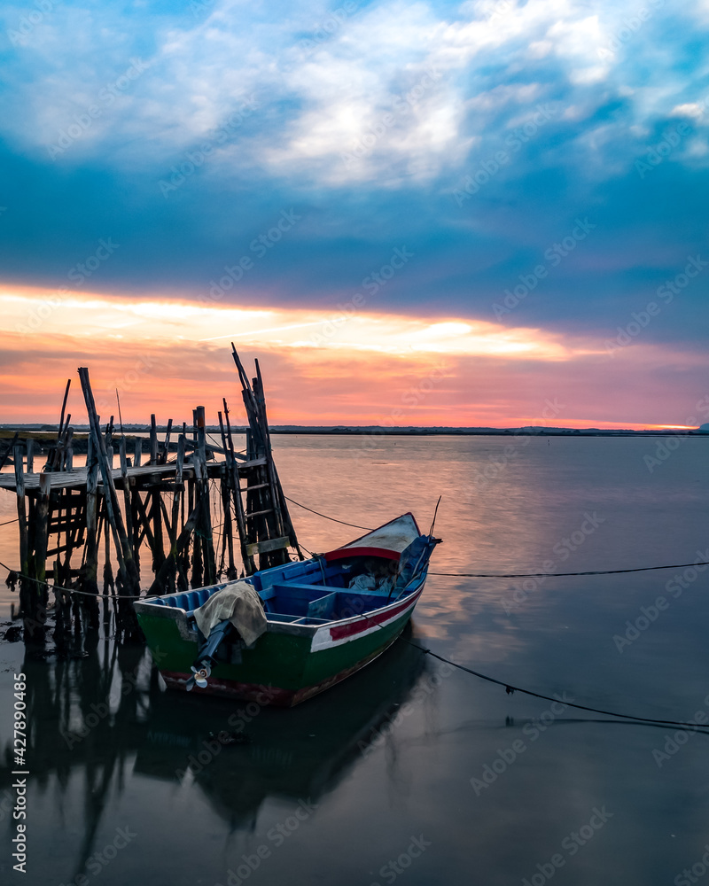 A fisherman boat at sunset on the Carrasqueira Palafitic pier in Comporta, Portugal.