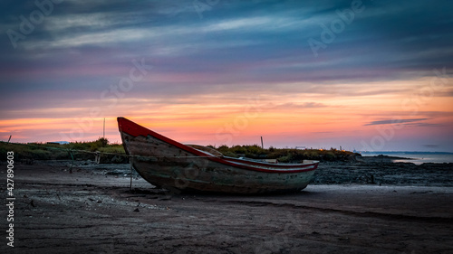 A fisherman boat on the beach at sunset next to the Carrasqueira Palafitic pier in Comporta  Portugal.