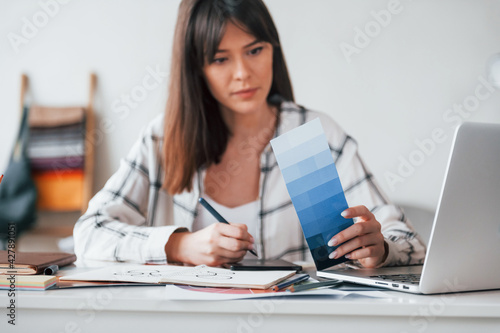 Doing paperwork. Young female freelance worker is indoors in home at daytime