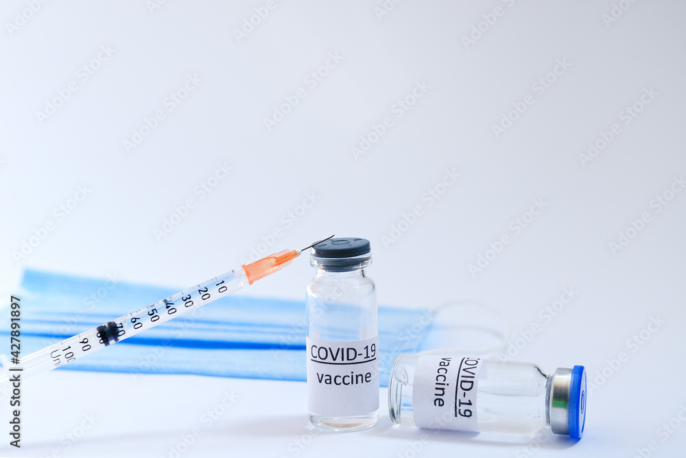 Creative ideas of vaccination concept. Top view of syringe with medical masks and vaccine vial glass bottles for vaccination against COVID-19. Coronavirus pandemic. Copy space. Creative ideas of vaccination concept. Top view of syringe with medical masks and vaccine vial glass bottles for vaccination against COVID-19. Coronavirus pandemic. Copy space.