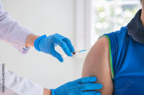 Doctor applying a vaccine on a male patient .