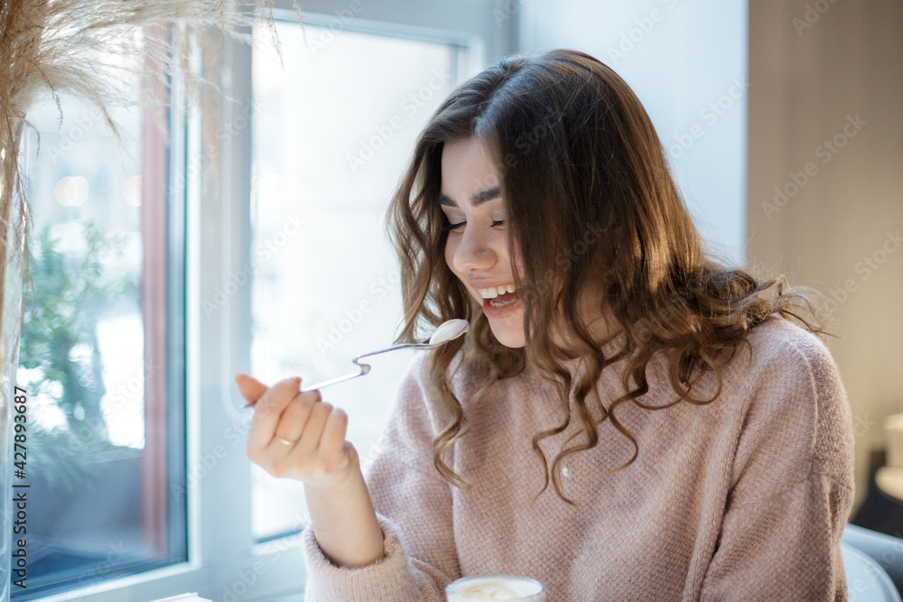 Beautiful young woman happy smiling sitting in restaurant or cafe and eating ice cream. Beautiful young woman happy smiling sitting in restaurant or cafe and eating ice cream.