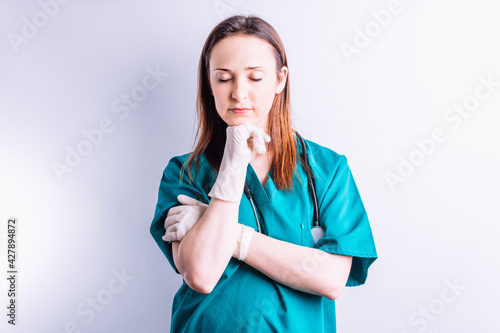 Hospital doctor surgeon with stethoscope and gloves with closed eyes tired leaning on her hand .Hospital medicine concept
