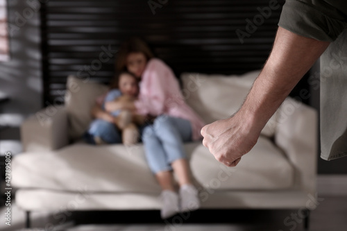 Man threatening his wife and daughter at home, closeup. Domestic violence photo