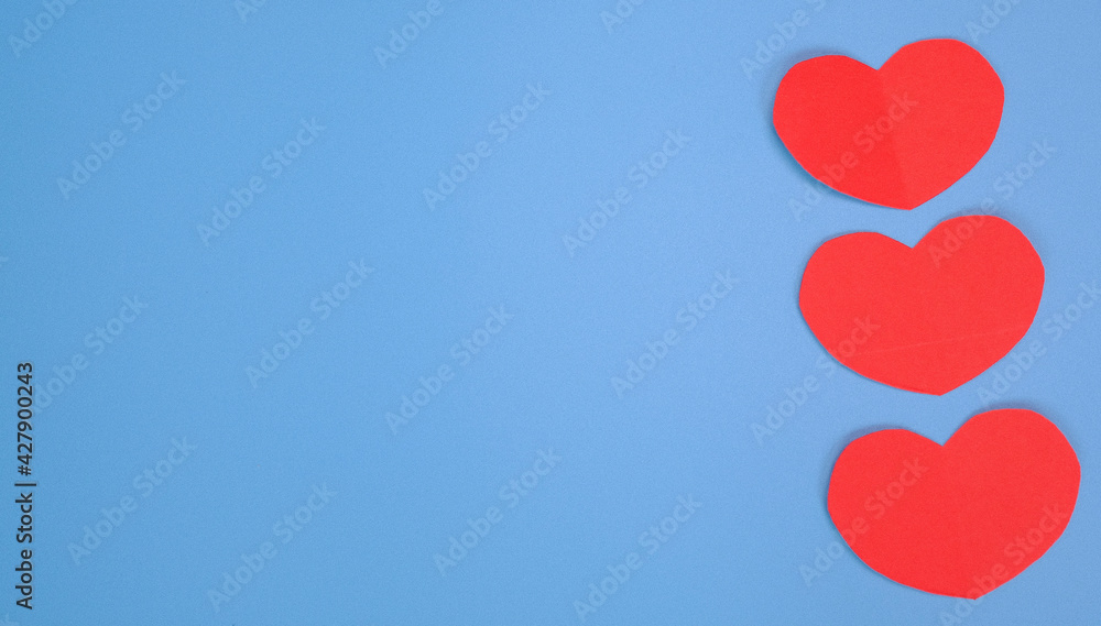 Red paper cut heart shape pasted on blue background
