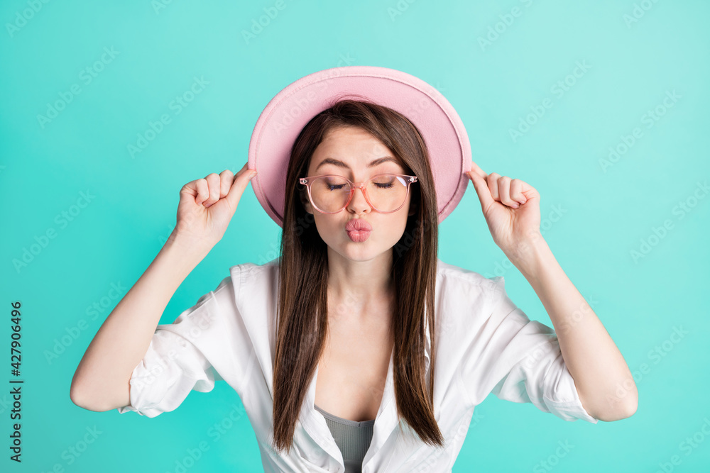 Photo of flirty charming young woman dressed white shirt glasses arms cap sending you kiss isolated teal color background Photo of flirty charming young woman dressed white shirt glasses arms cap sending you kiss isolated teal color background