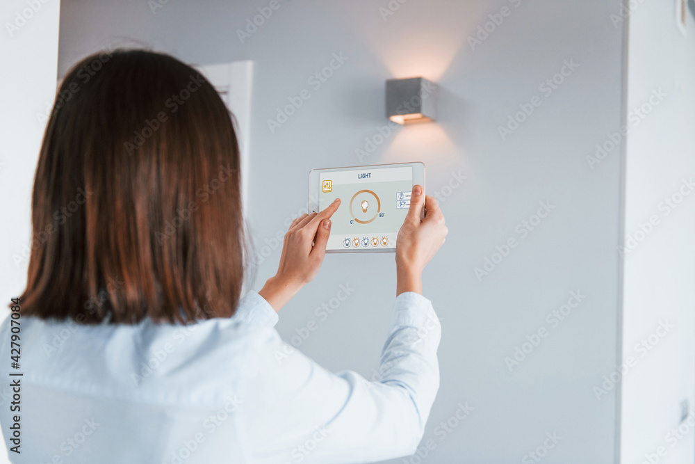 Rear view of woman that is indoors controlling smart home technology Rear view of woman that is indoors controlling smart home technology
