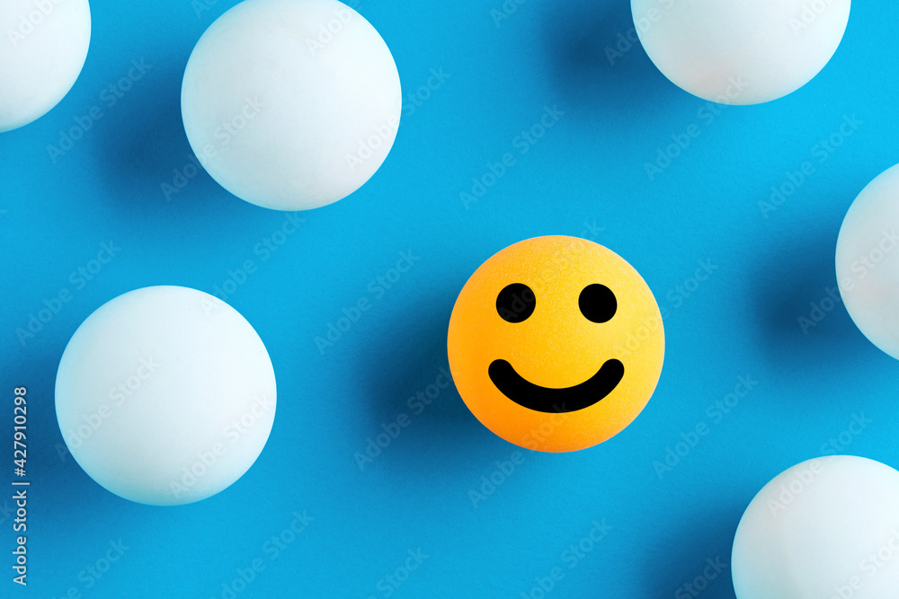 Smiling face emoticon or icon on a yellow ball surrounded by white balls Smiling face emoticon or icon on a yellow ball surrounded by white balls