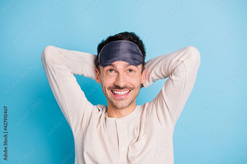Portrait of nice cheerful brunet guy wearing eye mask resting looking up isolated over bright blue color background Portrait of nice cheerful brunet guy wearing eye mask resting looking up isolated over bright blue color background