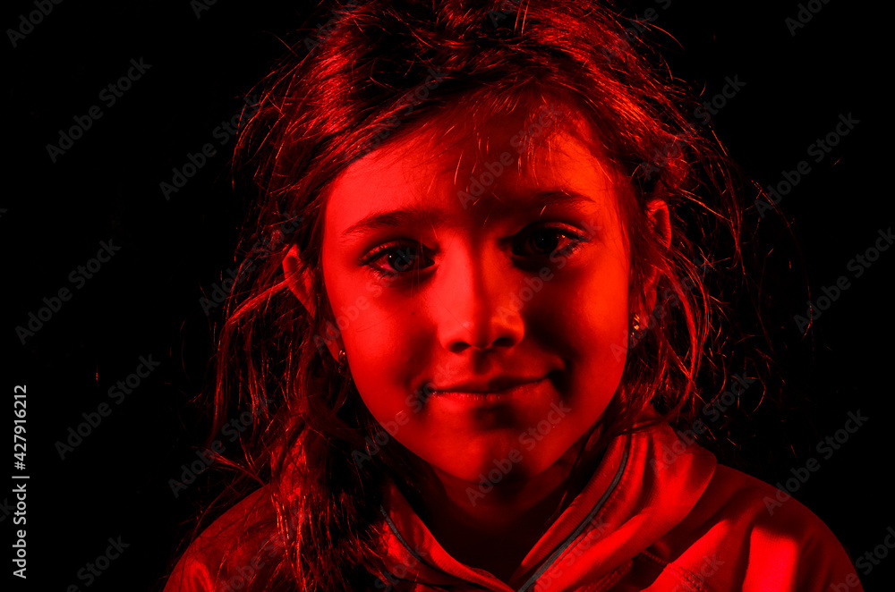 Red portrait of a child girl in a hood isolated on a black background Red portrait of a child girl in a hood isolated on a black background