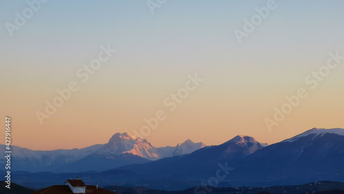 Tramonto primaverile sulle montagne innevate dell’Appennino e le colline e le valli delle Marche