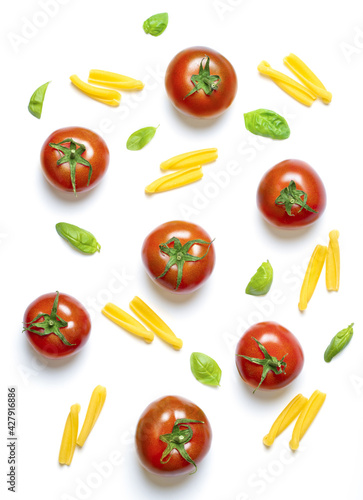 Tubular pasta type, cherry tomatoes and basil leaves arranged on white background.Top view. Mediterranean cuisine ingredients.
