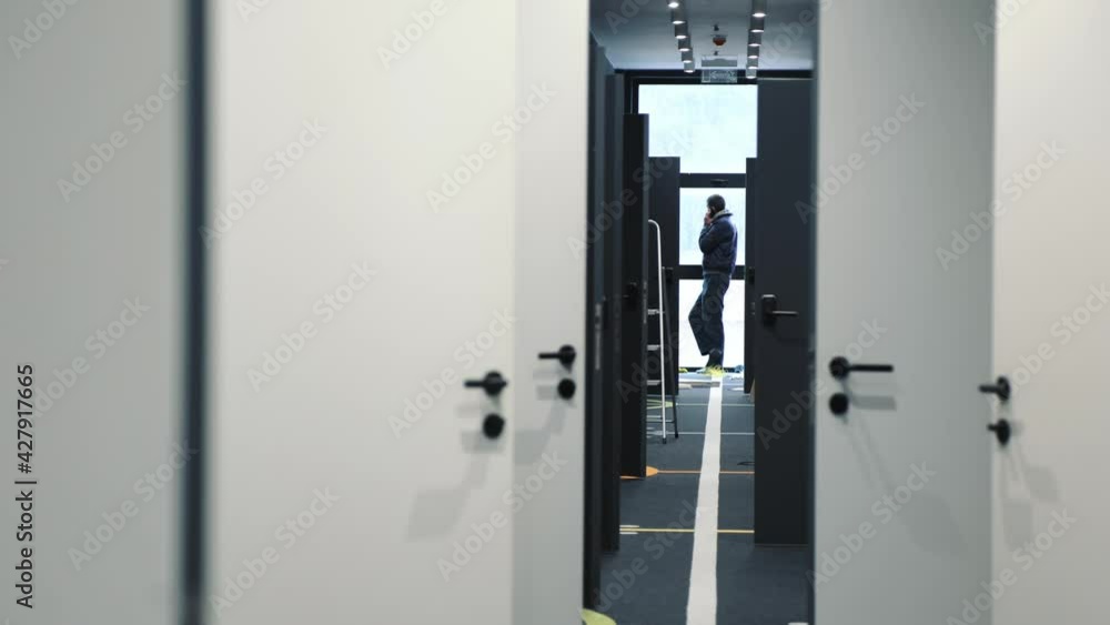 A man talking on the phone at the end of the corridor during the renovation of the house. A man talking on the phone at the end of the corridor during the renovation of the house.