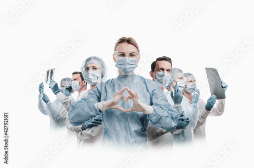 Obraz na płótnie medical workers heroes. a nurse in the foreground in a mask and uniform holds her hands in the shape of a heart. go to a lot of medical professionals. w salonie