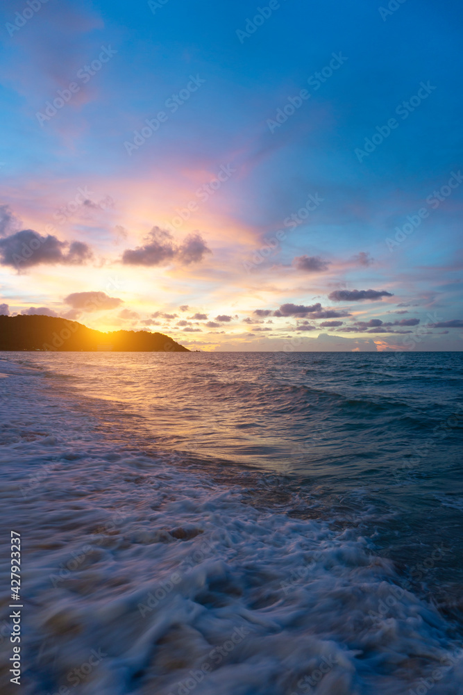 Summer time background beach, wave, sunset, cloud and blue sea as vertical image.