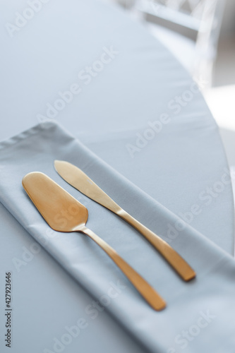 a gold-colored kitchen spatula and knife on a blue tablecloth