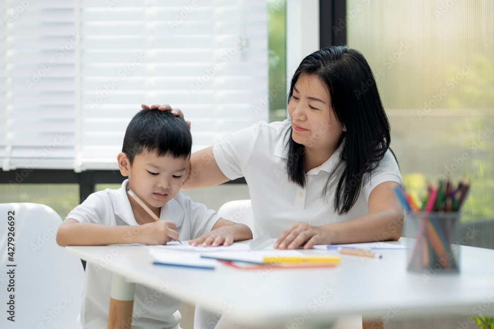 Mother and son doing homework at home, Mother is teaching son to draw pictures, Children homework. Young boy doing homework on the terrace at home. Happy mood. Back to school concept. Mother and son doing homework at home, Mother is teaching son to draw pictures, Children homework. Young boy doing homework on the terrace at home. Happy mood. Back to school concept.