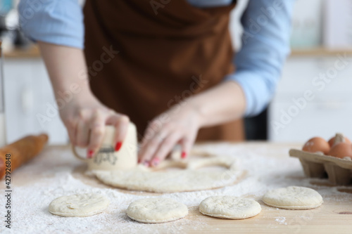 woman in the kitchen makes circles of dough with a glass