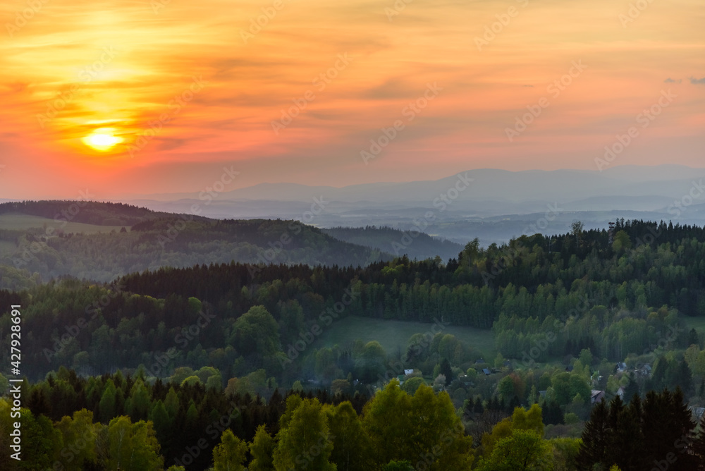An orange sunset over Orlicke hory and Krkonose mountains in the distance. 