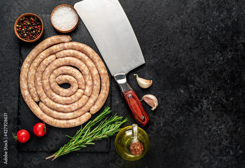 raw spiral chicken sausages with ingredients on stone background
