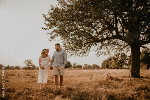 man in light natural clothes and shorts holds hand wife. Happy family pregnant caucasian