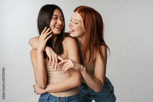 Multiracial two women hugging and laughing at camera